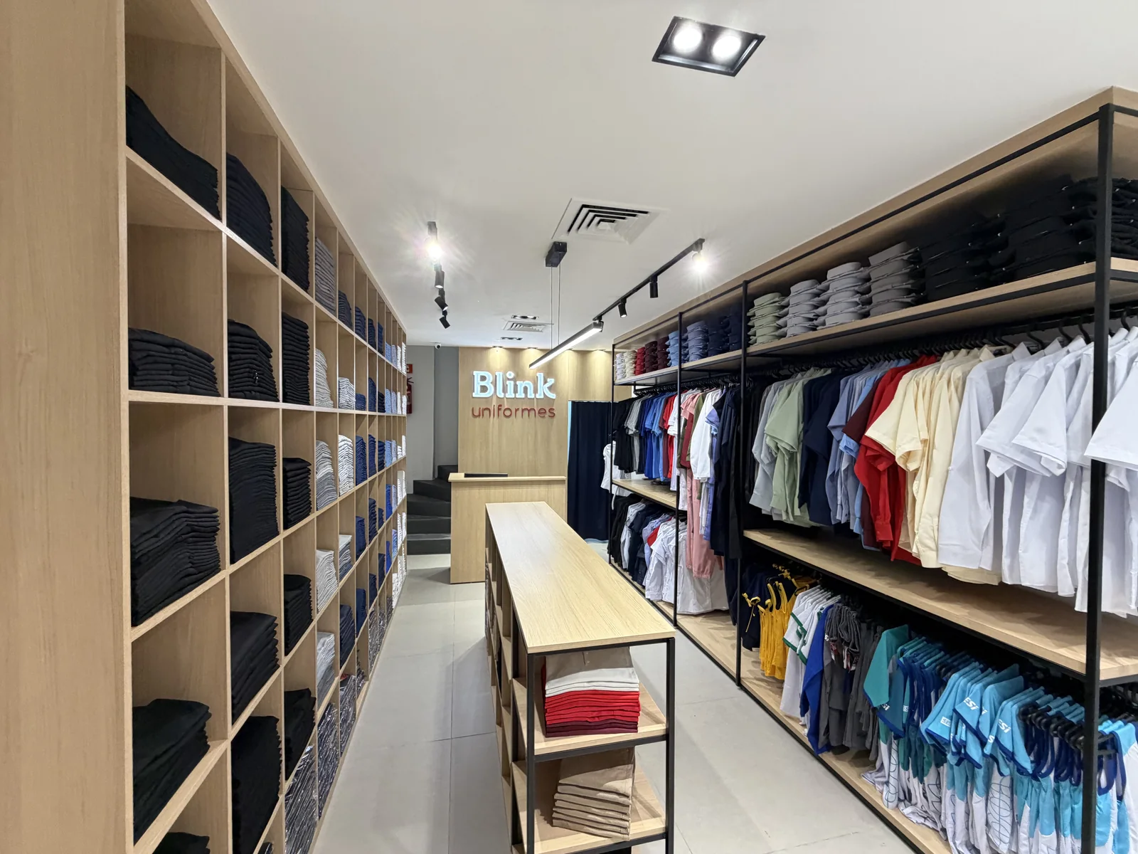Interior da loja Blink Uniformes em Vitória, com uniformes organizados e exposição de modelos